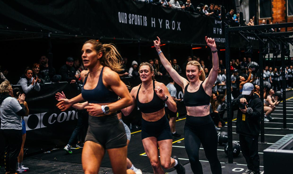 HYROX competitors running across the finish line as spectators watch on