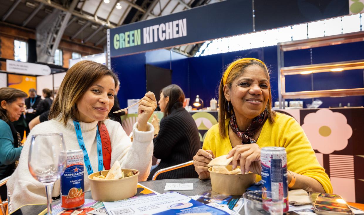 Customers enjoying food and drinks at a table, with the Green Kitchen retail point in the background